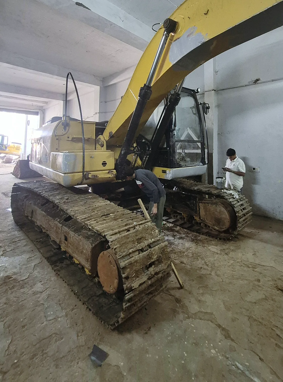 A worn CAT excavator being inspected